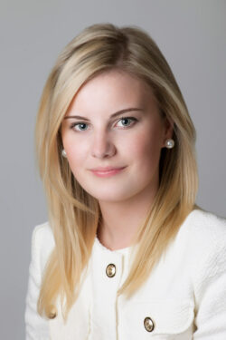 Professional headshot of a woman in a white textured blazer with gold buttons, taken in a Toronto studio by Exposures Photography.