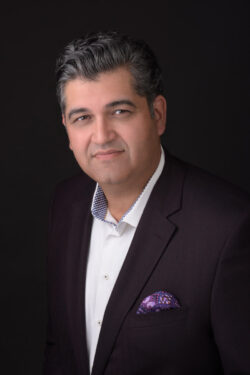 PExecutive business headshot of a man in a dark blazer and patterned pocket square, featuring professional studio lighting on a dark background, by a Toronto headshot photographer.